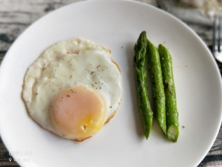 13、养颜营养早餐,煎好的鸡蛋装入盘子，芦笋装盘撒上胡椒粉