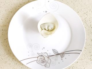7、#咸味#漂亮的馄饨太阳花,翻过来,就是一个漂亮的三角形小帽子,使其立起来,放在盘子的中心