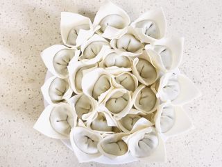 11、#咸味#漂亮的馄饨太阳花,按照这个原理,继续摆放第三圈和第四圈,都是插缝隙交叉摆放,直到最外圈,形成漂亮的太阳花,每个三角小帽子都要树立起来啊