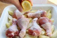 4、苹果柠香烤鸡腿,将腌了一晚的鸡腿摆在土豆上，并挤点柠檬汁在鸡腿上。注：柠檬汁的作用去异味，增香，这里我们没有用姜