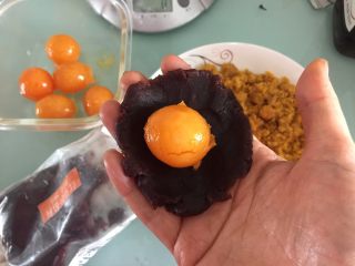 4、蛋黄豆沙蔓越莓包,取30克豆沙压扁，中间放上一颗咸蛋黄，我的大概16克左右