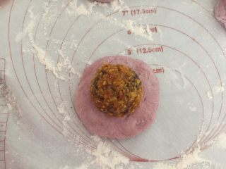 10、蛋黄豆沙蔓越莓包,取一个小面团压扁，四周弄薄点，中间放上馅料团