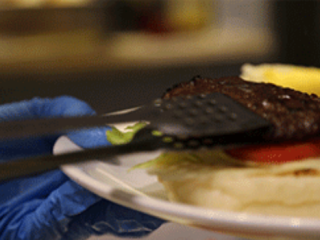 7、芝士酱牛肉汉堡,将烤熟的牛肉饼放在蔬菜上。