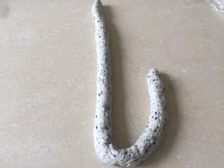 16、佛系养生黑芝麻辫子面包,第十六步：搓长后取一根面团先放成L形