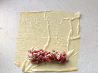 10、腐皮肉馅卷,平铺在台面上，在尾部一端放适量肉馅，如图