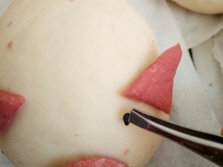 17、萌萌的小猪包,用镊子夹上黑芝麻插上眼睛。