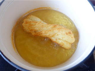 10、自制健康油条,放入油条,用筷子不停翻动,炸至色泽金黄,将油条捞出。