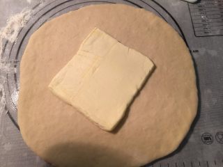 4、起酥手撕包,把发酵好的面团用手压出气体，放在室温静置松弛30分钟。在面团松弛的时候，可以准备裹入用的黄油了：把70克黄油切成片，提前平铺在保鲜袋里，用擀面杖擀开成正方形