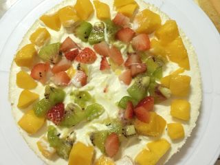 13、缤纷水果奶油蛋糕,取一片蛋糕放在裱花台中间，抹上一层奶油，放入适量的水果，中间留出空间放水果