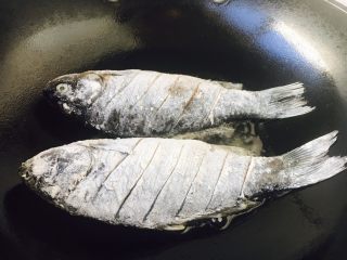 6、#感恩节食谱# 红烧鲫鱼,大火起锅，锅热放入约3勺左右的油，当油六成热时放入鱼，此时改中火。 煎鱼时随时微微调整火的大小，千万不要让油起烟。 六成热的油温是如何判断呢，就是油面有明显的波动。 往油锅里放鱼时，用双手分别拎住鱼头和鱼尾，贴着油面轻轻地放入。 我使用的是不粘锅。 如果小伙伴们使用的是铁锅就要把锅烧的热热的，然后用姜在锅里涂抹一层，再继续操作。