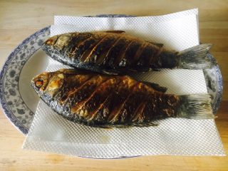 8、#感恩节食谱# 红烧鲫鱼,煎好的鱼沥一下油。 最传统的沥油方法是把鱼放在笊篱上沥油。 我的这个方法也不错吧。