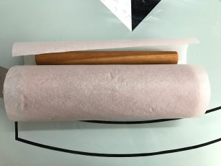 10、黑米戚风蛋糕卷,借助擀面杖将蛋糕卷起来，用油纸卷起来放入冰箱冷藏定形30分钟以上。