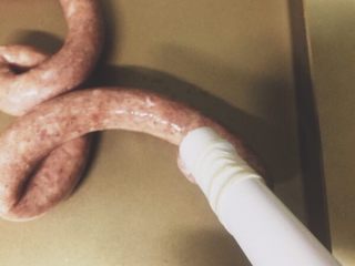 13、黑胡椒味台式脆皮肠（内附广式配方）,肠衣一头打结，一头套在灌肠神器上，把调好的肉馅塞到神器中，再灌到肠衣中。如果打进空气，肠一边有空隙，可以用针扎一下，再多灌些肉进去。