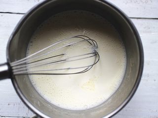 4、葡萄干奶冻,然后倒入奶锅内，电磁炉小火加热，一边加热，一边用蛋抽不断搅拌。直到煮到微微冒泡，即可关火