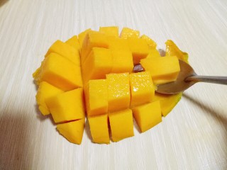 8、#冬喝暖饮夏吃冰#健康低卡-芒果酸奶昔,再用勺子将芒果肉挖下来。