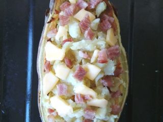 8、红薯奶酪焗蛋,将挖出的红薯肉撒一些在上面，将剩余的培根和奶酪丁洒好，刮成薄片的黄油也放好，再入烤箱180度，单开上火，3-5分钟，将培根烤熟，奶酪烤化即可