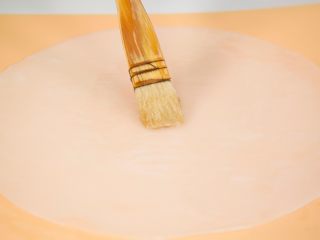 8、自制健康凉皮,用水冲凉凉皮锣子后取出凉皮,放入盆里,再在上面刷层油防粘。