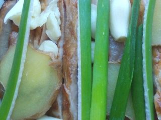 7、家常南乳扣肉,猪皮朝下，码在深盘或大碗中，上面放适量姜片，葱和蒜片