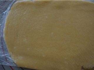 12、好吃的切达芝士酥饼,为了防止粘黏，将装面团的保鲜袋展开放在硅胶垫上，再将余下的折过来铺在面团上面，擀成0.8CM厚的大片。