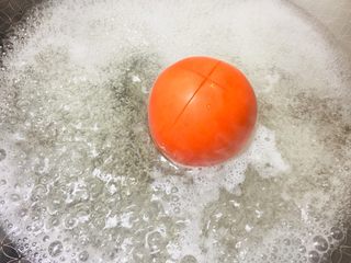 2、#懒人料理#茄汁酸甜金针菇,西红柿顶部用刀划十字口，开水后放进去煮开皮。