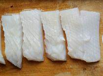 5、生炒墨鱼,再竖着片出间隔约3mm的平行刀纹，每6～7刀切断一次，即成长5cm、宽2cm的麦穗花刀块