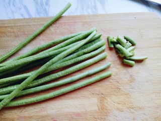 2、长豇豆棒棒糖,将长豇豆整齐的放在砧板上,切去根和尖。(切整齐,长短一致。)