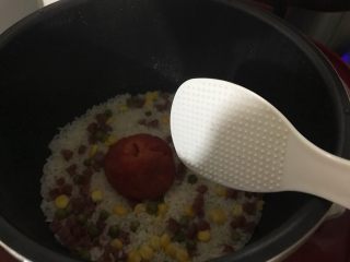 11、抖音网红菜谱-五彩西红柿焖饭,待电饭煲完成工作，打开锅盖，用饭勺翻拌，捣烂西红柿
