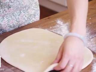 4、丹麦酥皮面包,把面团放在撒了干粉的案板上，用擀面杖压扁擀成长方形面片