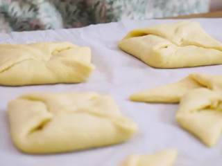 12、丹麦酥皮面包,做好的面包放在有烘焙纸的烤盘中，盖上保鲜膜等面醒发