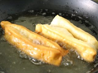 12、自制健康蓬松油条,油条会慢慢变大，呈现金黄色即可捞出。