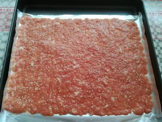 12、自制猪肉脯,把肉沫转移到烤盘里,刷一层蜂蜜水,再撒上适量的白芝麻,预热烤箱上火150度,下火160度