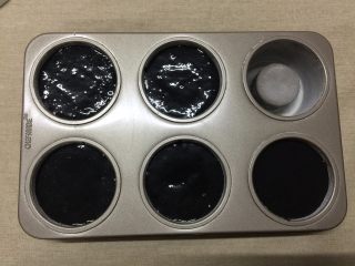 11、奶油黑杯子,往模具内倒入蛋糕糊，左右晃动使蛋糕糊平整，轻震几下震出大气泡