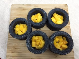 16、奶油黑杯子,往蛋糕加入芒果肉