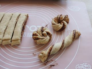 7、巧克力面包卷,取一长条，捏住两头，头尾反向扭几卷，然后头尾交叉，将搭在上边的那一头往下穿上来。