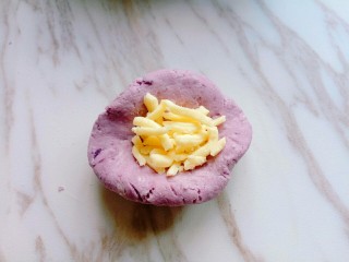 9、芝士紫薯球#附紫薯泥制作#,取一小块面团，用手心压扁，加入马苏里拉芝士，包包子的手法抱起来，收口朝下，捏紧，揉圆。