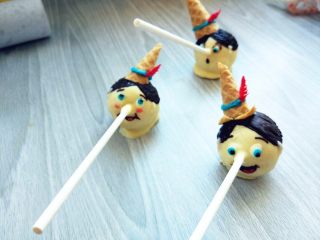 13、皮诺曹棒棒糖蛋糕,再画好帽子的蓝色围边，用红色巧克力在油纸上画出羽毛，装饰好即可。