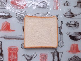 14、日式鸡胸肉蛋三明治,取一张保鲜膜铺在砧板上,放上一片吐司