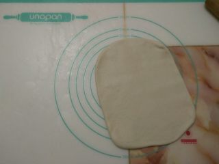 6、蔓越莓手撕包,取出冷冻的面团，用擀面杖擀开，翻面继续擀开成长方形。