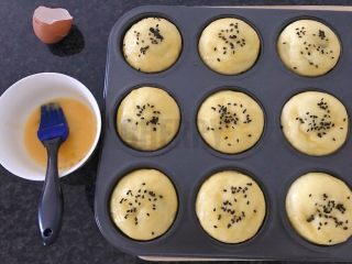 17、#家有烤箱#黑芝麻豆沙面包,再次发酵后，打散鸡蛋，用刷子轻轻在每个面团上涂抹一层蛋液，撒些黑芝麻，