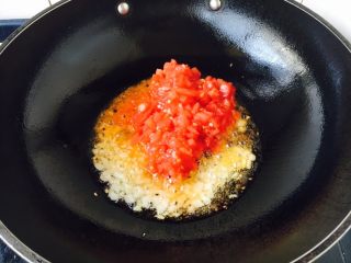 6、番茄金针菇肥牛,起锅，热锅凉油，中火，放入洋葱碎和蒜末，煸炒出香味，放入番茄碎，翻炒均匀。