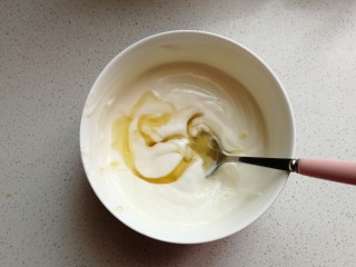 4、芒果酸奶雪糕,浓稠酸奶倒入容器中，加入适量蜂蜜，用手动打蛋器搅打均匀。