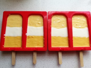 11、芒果酸奶雪糕,再轻轻震荡几下震平表面，可以借助牙签来回划动，用牙签划动即能平整表面又能划出里面的气泡空洞。