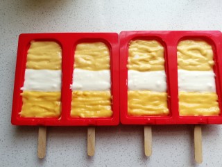 10、芒果酸奶雪糕,再如图交错着把三份酸奶糊挤入硅胶雪糕模中。