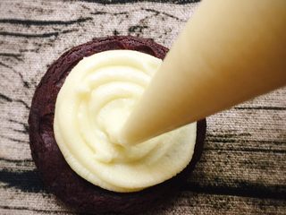 17、扭一扭，舔一舔，再泡一泡,取一片冷却好的饼干，底部朝上，挤上满满的一层巧克力馅，最好是从中间向外挤。如果熟练了可以就在中心位置挤