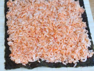 3、韩式紫菜包饭便当,将寿司紫菜铺在寿司帘上,把米饭铺匀。