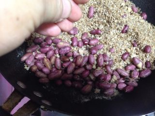 10、盐焗鲜花生米,把花生米拨到锅的一边，用手在花生米上弹少许清水