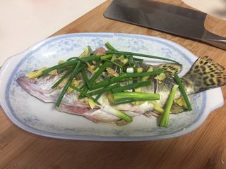 2、清蒸鳜鱼,全身抹上细盐，料酒，把鱼按摩几下，这样让盐和料酒更均匀的抹在鱼身上，上面撒上姜和葱段，腌制半小时。