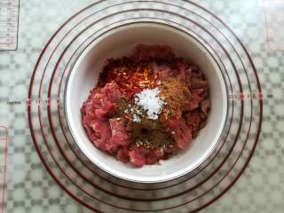 4、孜然牛肉串,准备一个大碗，在牛肉上放入孜然粉，五香粉，辣椒和盐简单混合