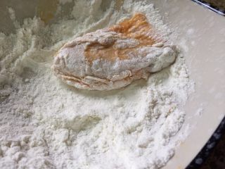 6、无油版黄金烤翅,取一个鸡翅，首先在面粉里滚下；让鸡翅全身都粘满粉剂；