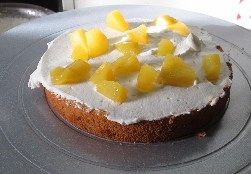 15、玫瑰奶油蛋糕,取一片蛋糕片放在裱花台上，然后抹上一层奶油。在加上黄桃粒